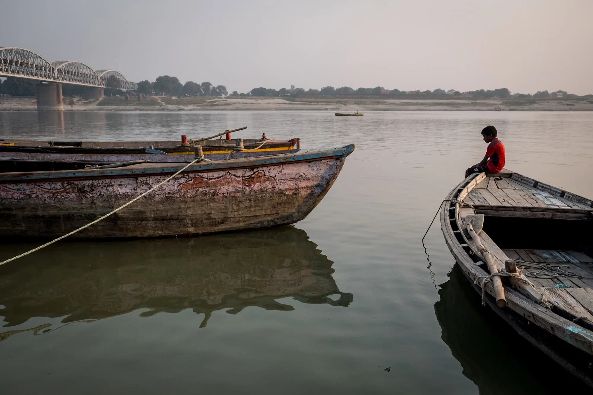 boy sitting on boat on the Ganges taken by Indian street photographer