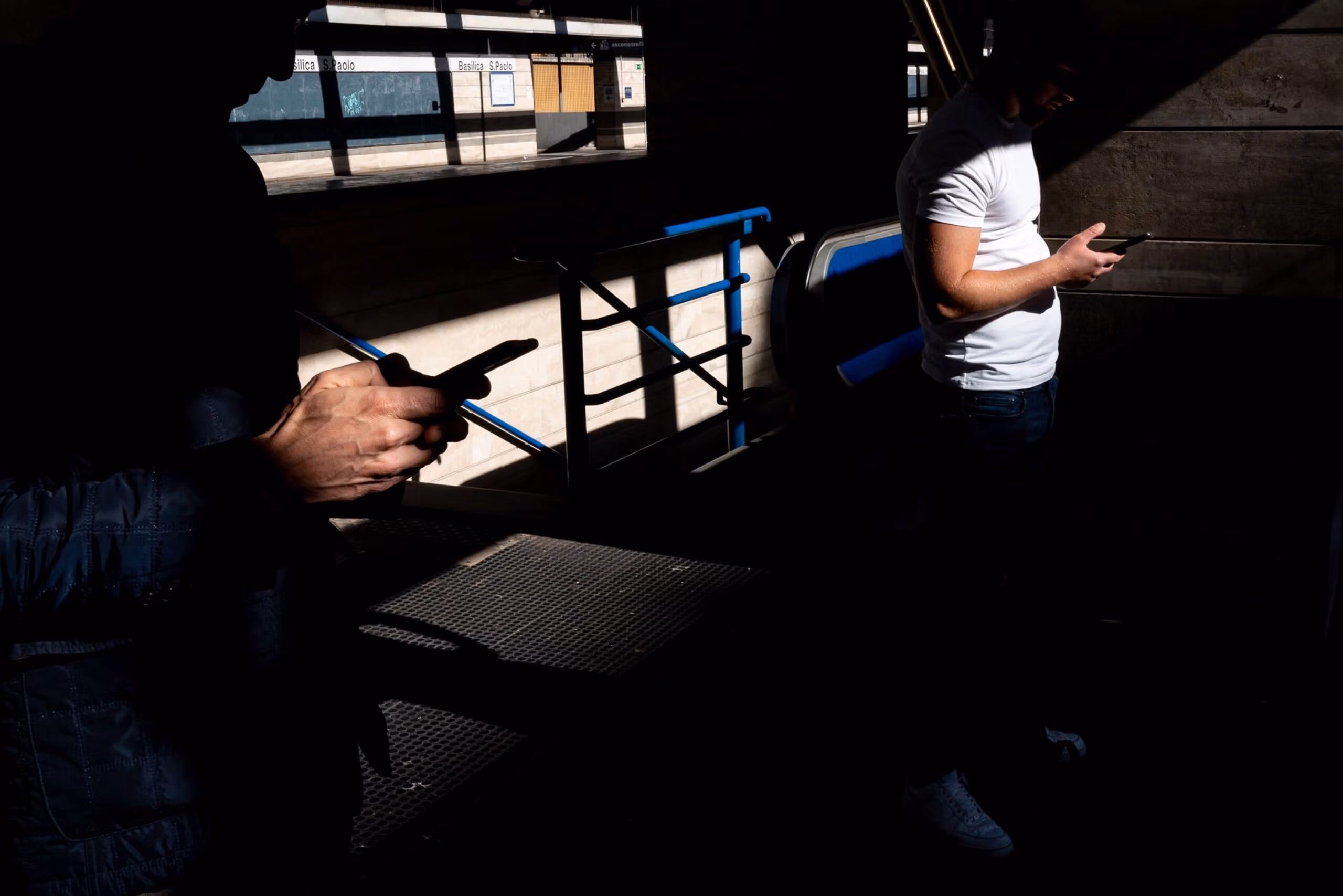 photo of two men on their phones listening to street photography podcasts