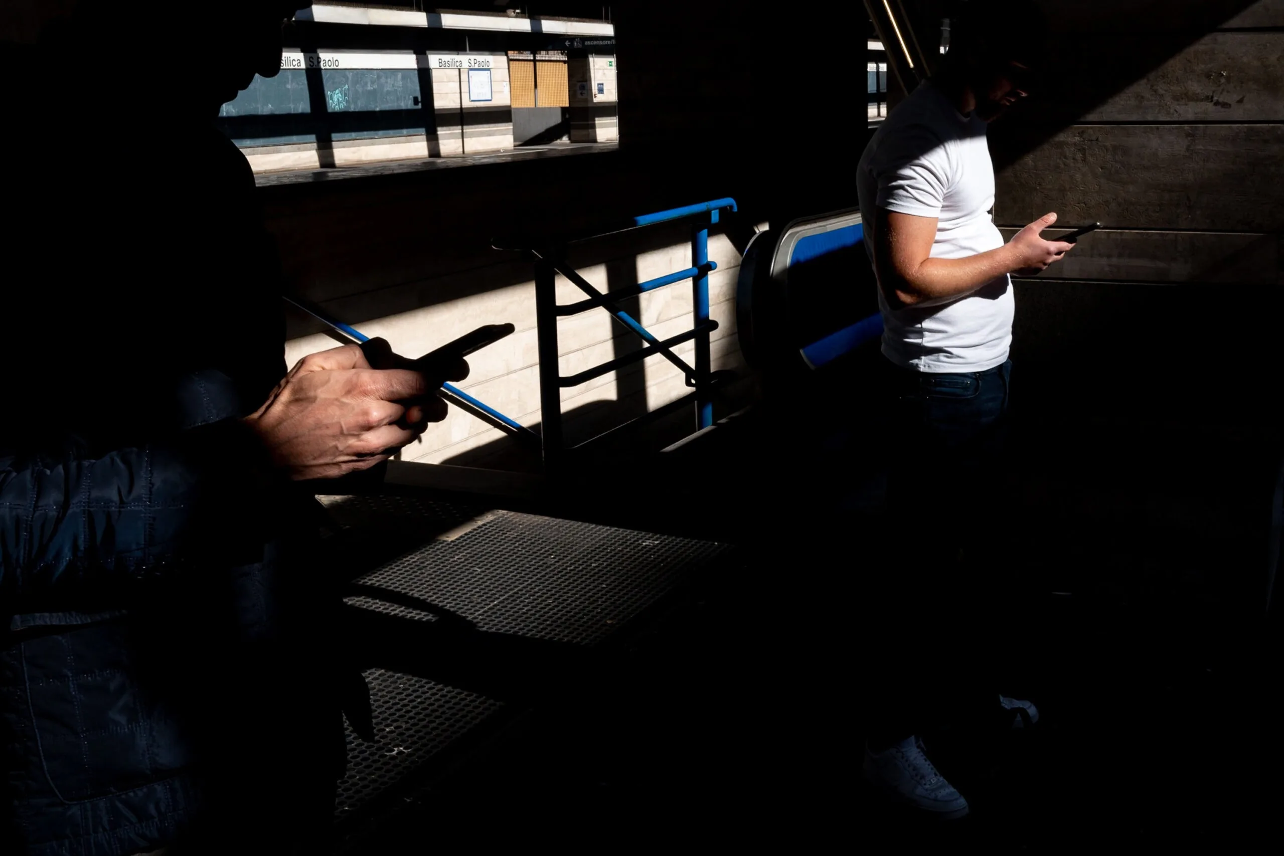 photo of two men on their phones listening to street photography podcasts
